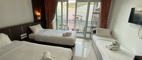 A hotel room with two beds, a TV, and a balcony with a table and chairs.