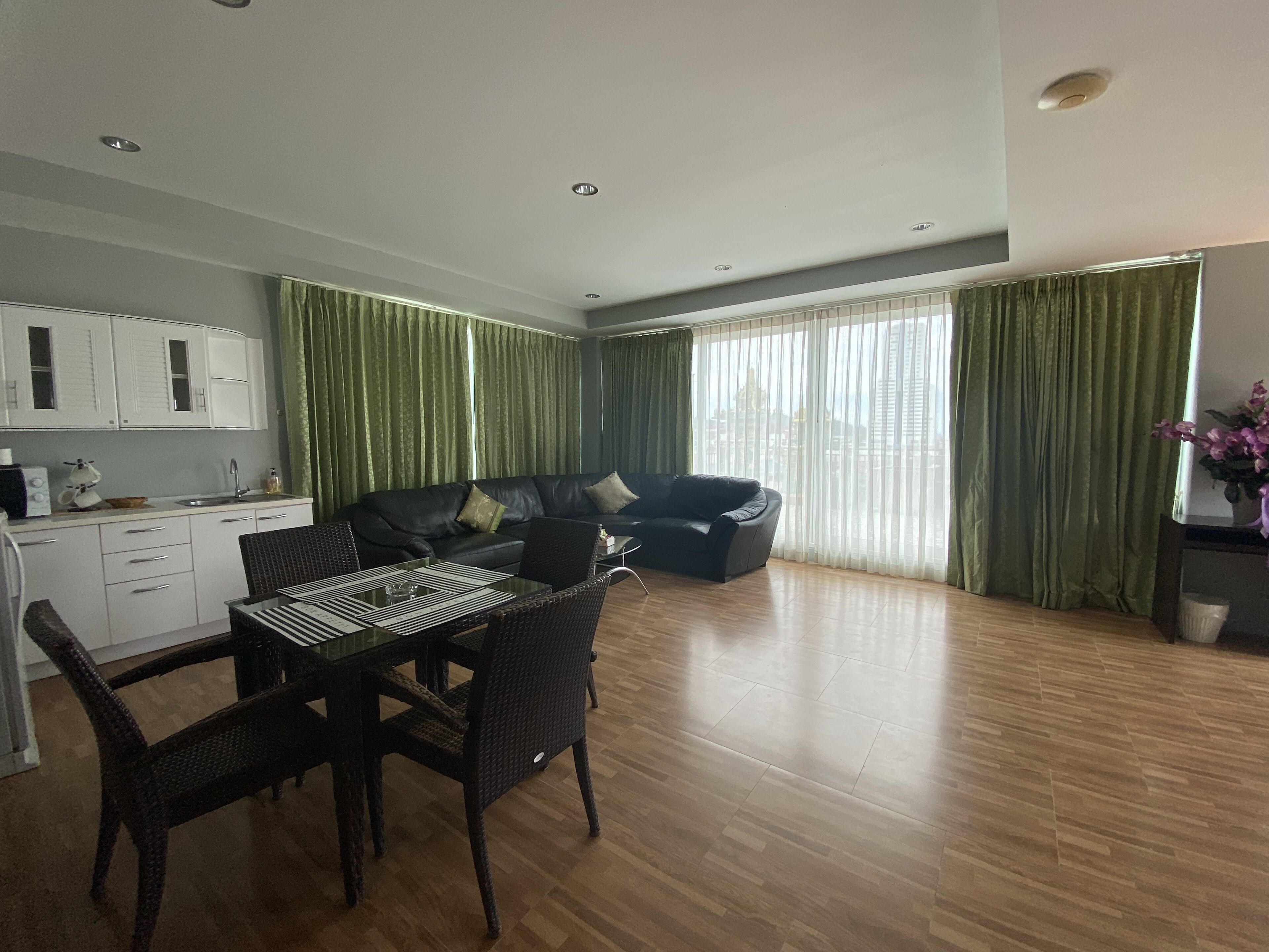 A modern living room with a dining area, a sofa, and a kitchen in the background.