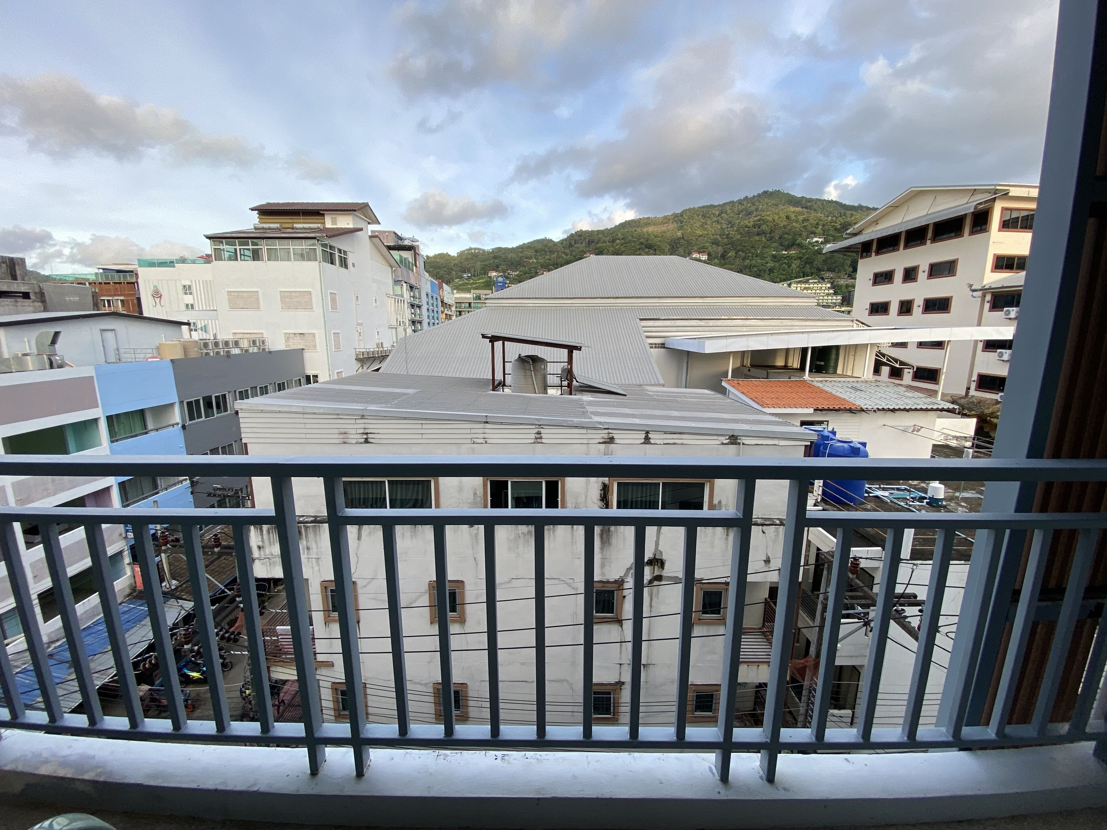 A view from a balcony overlooking a residential area with buildings and a hill in the background.
