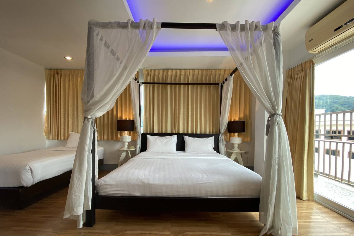 Ein Hotelzimmer mit einem großen Bett, zwei Nachttischen mit Lampen, einem Himmelbett und Blick auf einen Balkon.