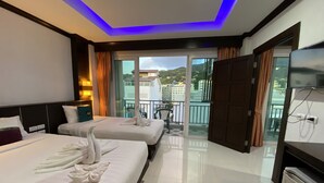 A hotel room with two beds, a balcony with a view, and a TV. - 77 Patong Hotel & Spa (Patong)