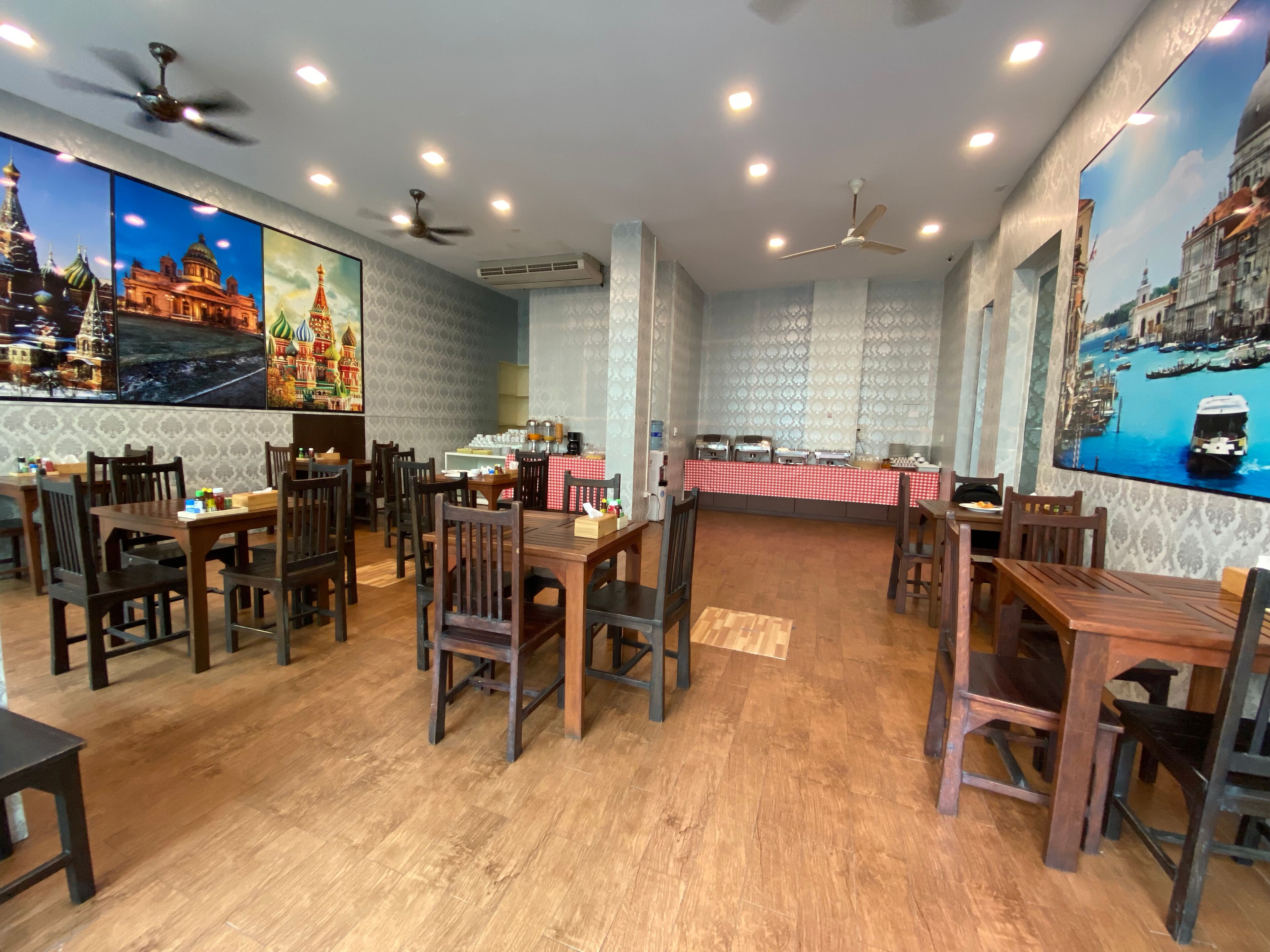 A restaurant with wooden tables and chairs, ceiling fans, and wall-mounted air conditioning units.