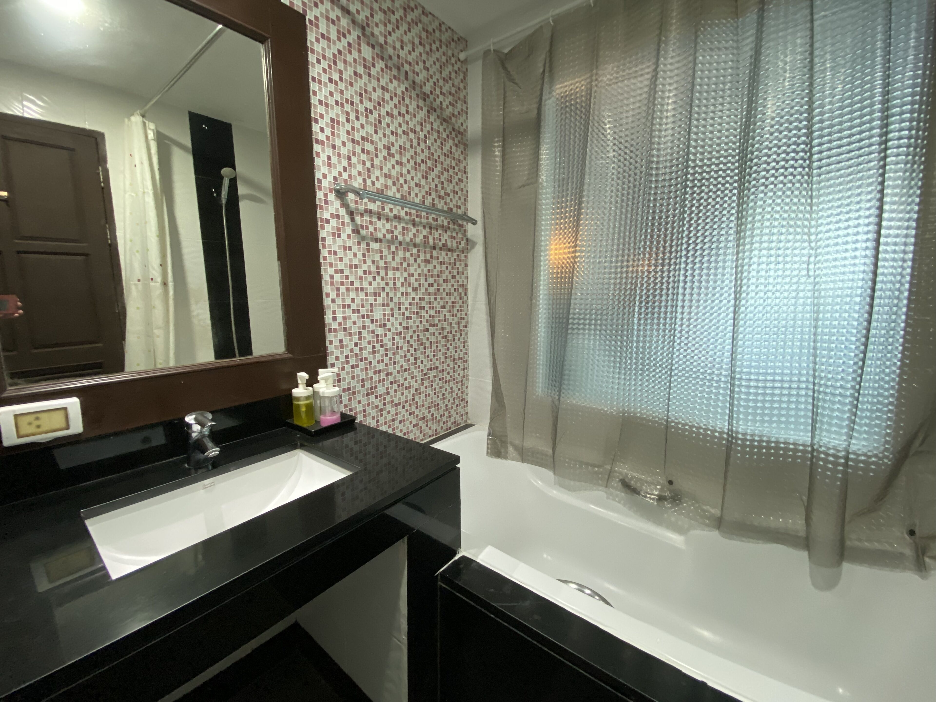 A bathroom with a black countertop, a white sink, a mirror, and a shower area with a frosted glass door.