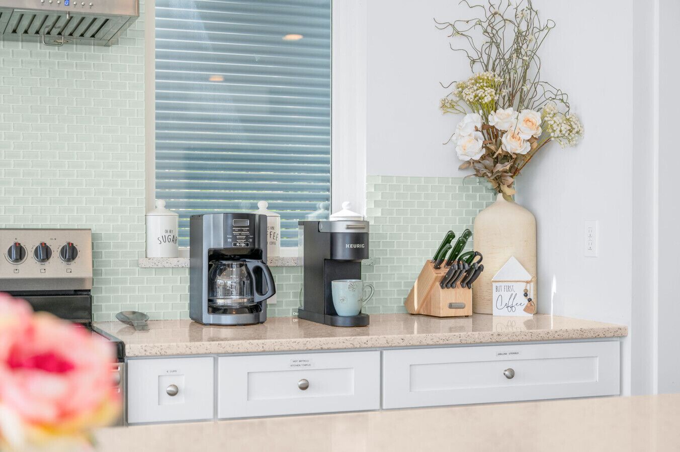 A modern kitchen with a coffee maker, a knife block, and a decorative vase.
