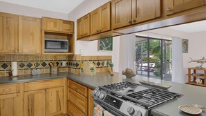 Une cuisine avec des meubles en bois, un four à micro-ondes, une cuisinière et un dosseret carrelé.