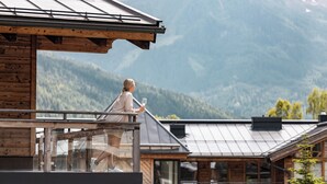 Eine Person auf einem Balkon mit Blick auf eine gebirgige Landschaft.