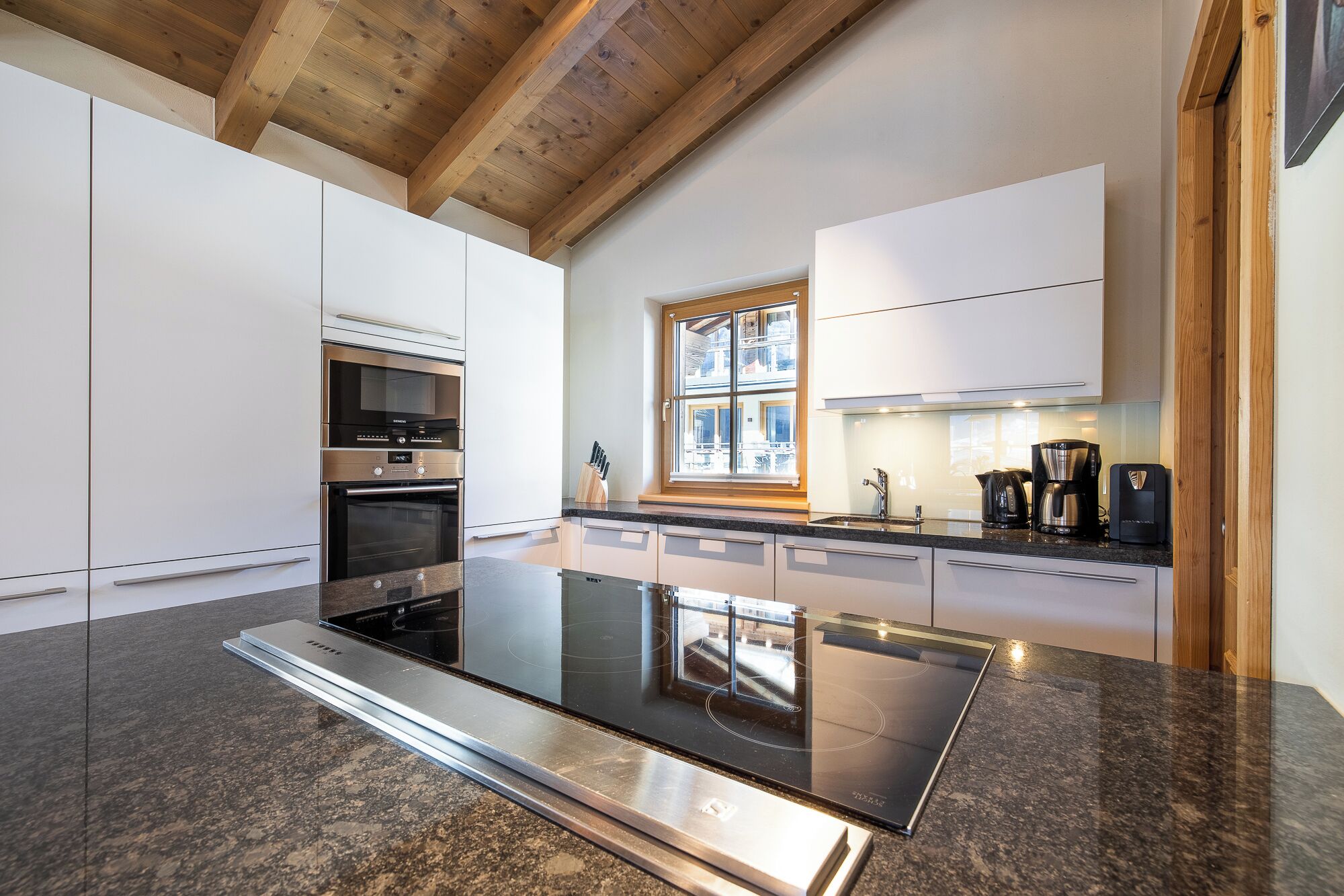 Una cocina moderna con una isla central, horno empotrado y ventana con vistas a la ciudad.