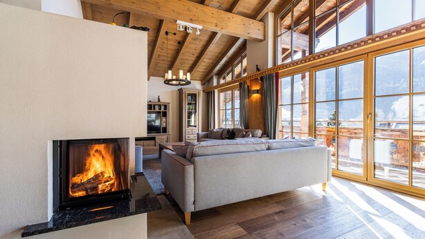 Ein geräumiges Wohnzimmer mit Kamin, großen Fenstern und einer gemütlichen Sitzecke.