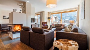 Ein gemütliches Wohnzimmer mit Kamin, bequemen Sitzgelegenheiten und Bergblick.