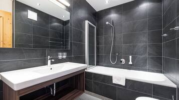 Un baño moderno con un espejo grande, un lavabo blanco, una bañera y una ducha.