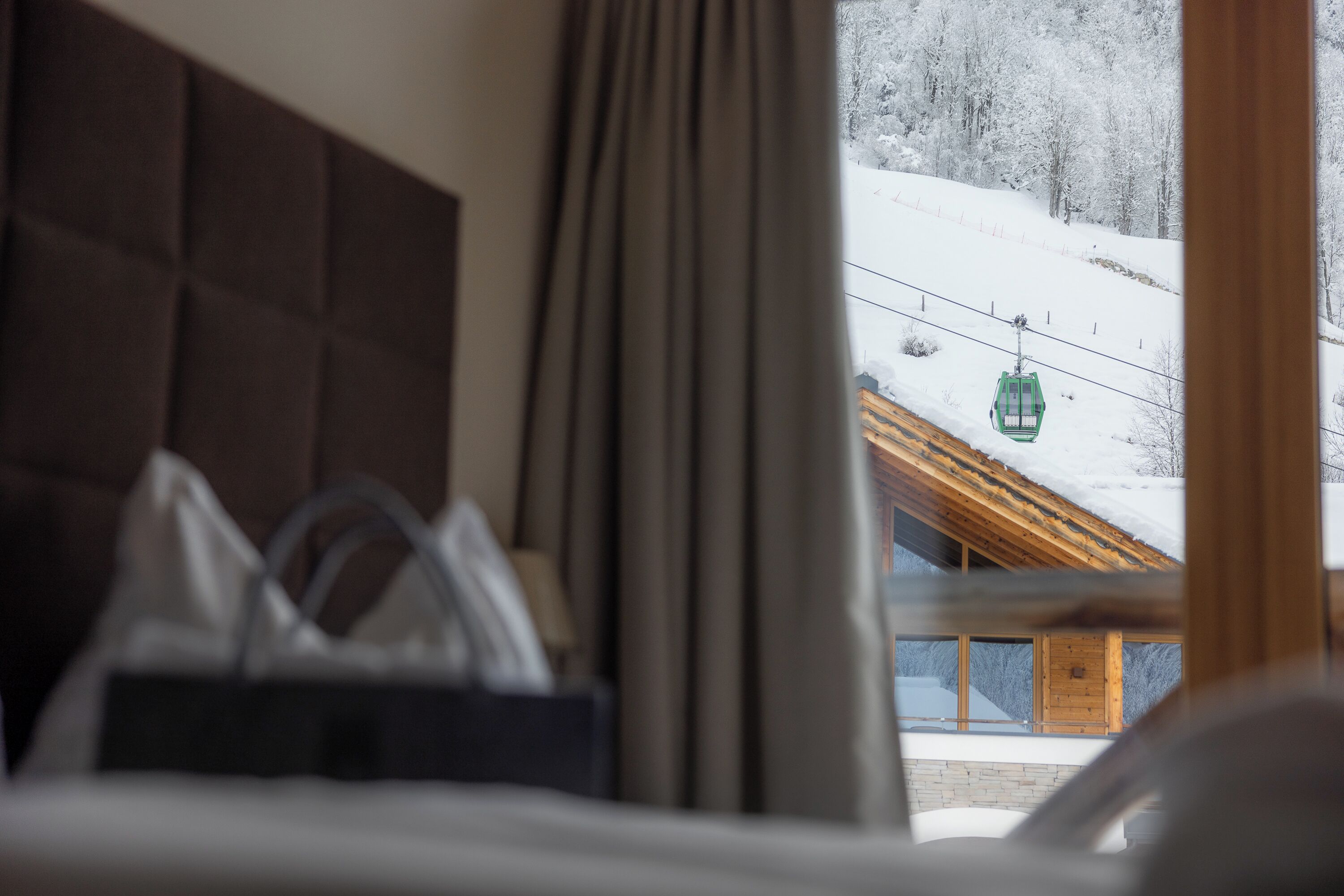 Habitación de hotel con vista a un paisaje nevado y un telesilla.