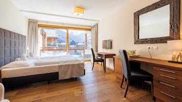 Une chambre d’hôtel équipée d’un lit, d’un bureau, d’une chaise et d’une grande fenêtre donnant sur les montagnes.