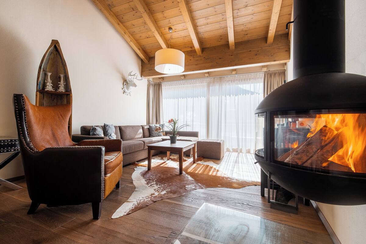 Un salón acogedor con chimenea, vigas de madera en el techo y decoración rústica.