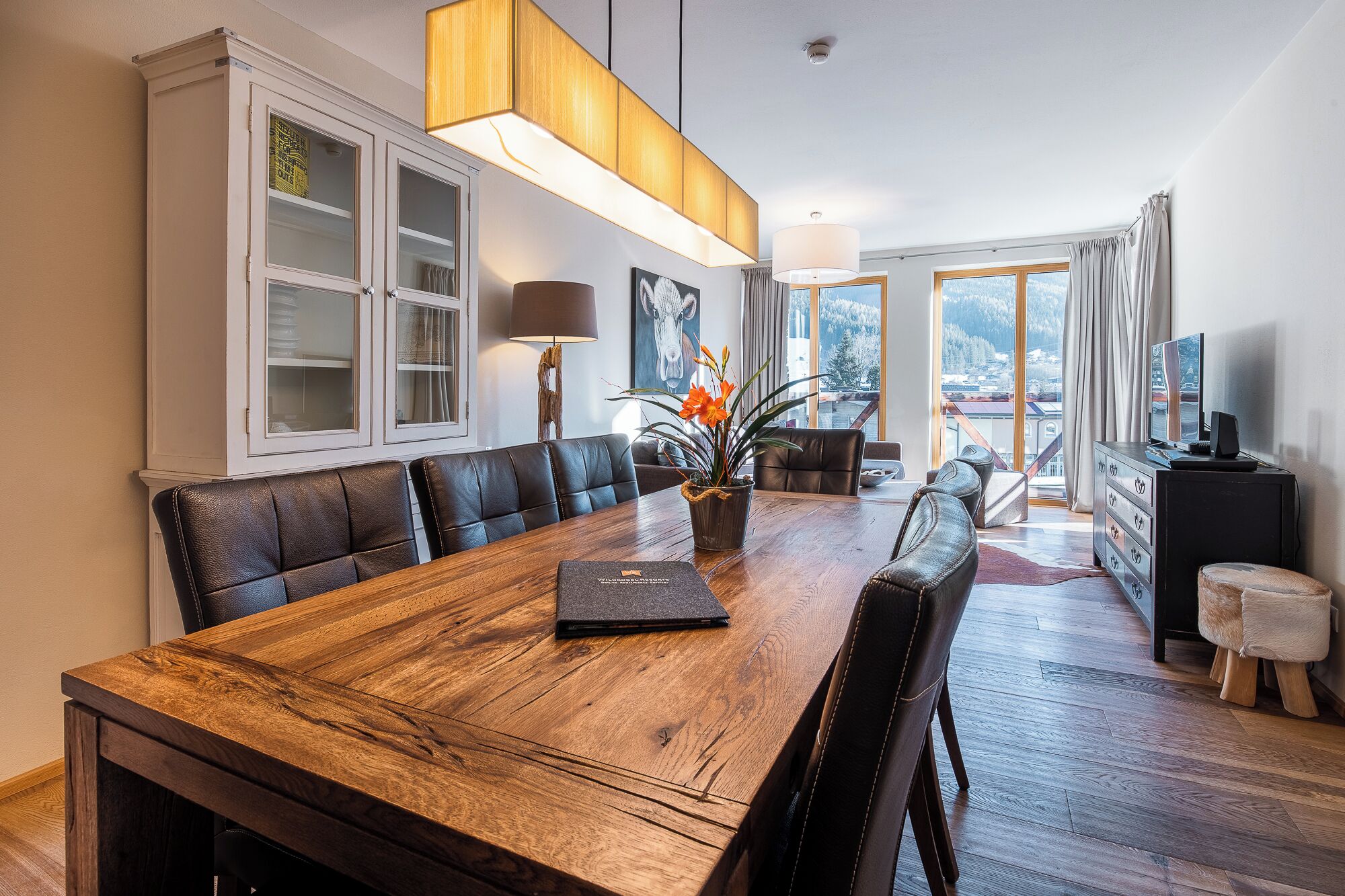 Un vaste espace dédié à la salle à manger, avec une table en bois, des sièges en cuir et une vue sur un paysage enneigé grâce à de grandes fenêtres.