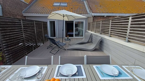 Una terrazza sul tetto con area pranzo, comprensiva di tavoli, sedie e una ciotola di frutta.