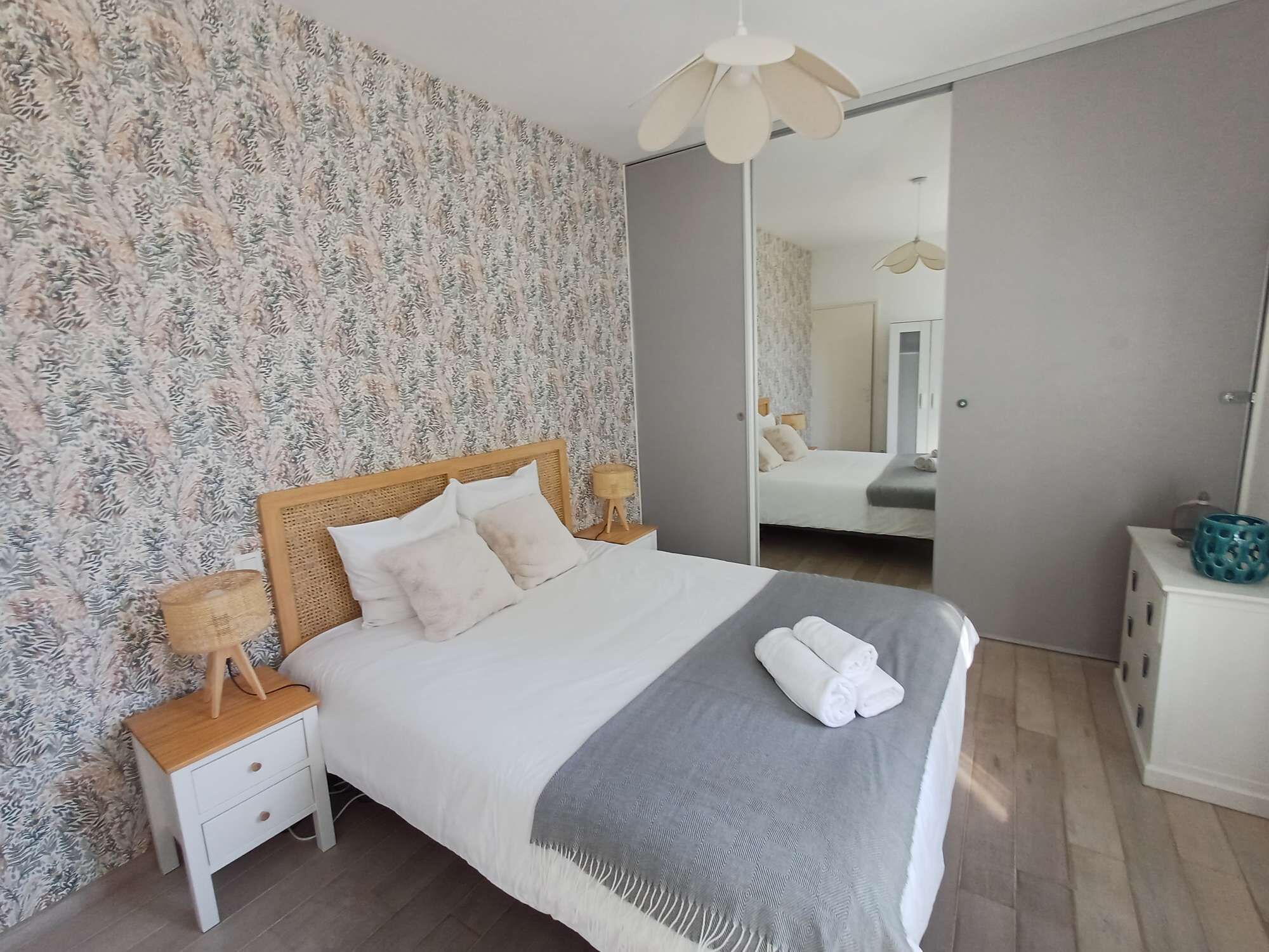 Quarto com cama, mesas de cabeceira, espelho e guarda-roupa.