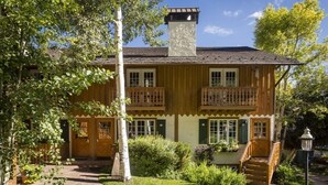 Een traditioneel houten huis met een balkon, schoorsteen en een stenen pad naar de ingang.