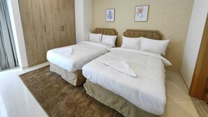 Quarto de hotel com duas camas, um guarda-roupa de madeira e duas obras de arte florais emolduradas na parede.