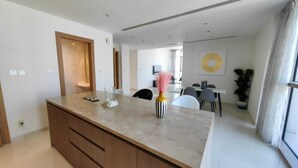 Cozinha moderna com ilha central, armários de madeira e área de refeições com mesa e cadeiras.