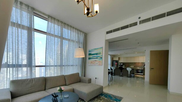 Uma sala de estar moderna com um sofá, uma mesa de centro e grandes janelas.
