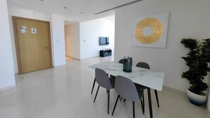 Uma sala de jantar moderna com uma mesa de mármore, cadeiras cinzentas, uma grande obra de arte feita de fibras e um vaso de planta.