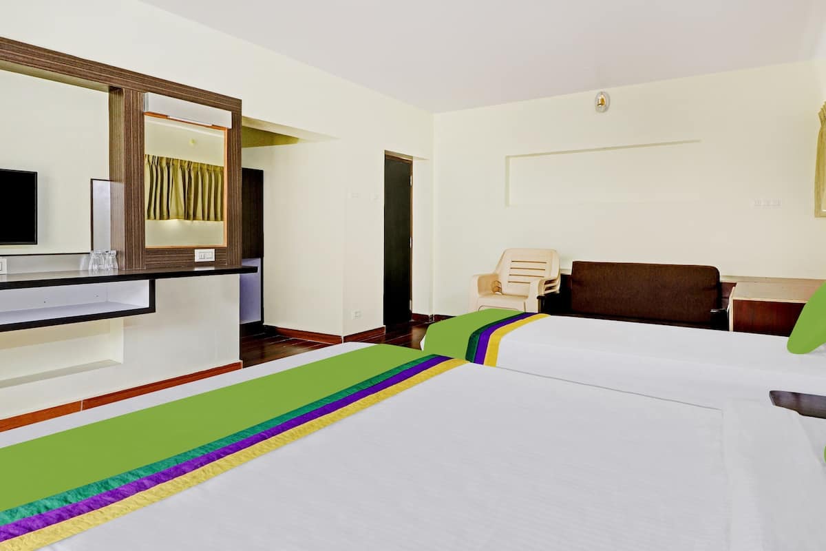 Een hotelkamer met een bed, een stoel, een bureau, een spiegel en een televisie.