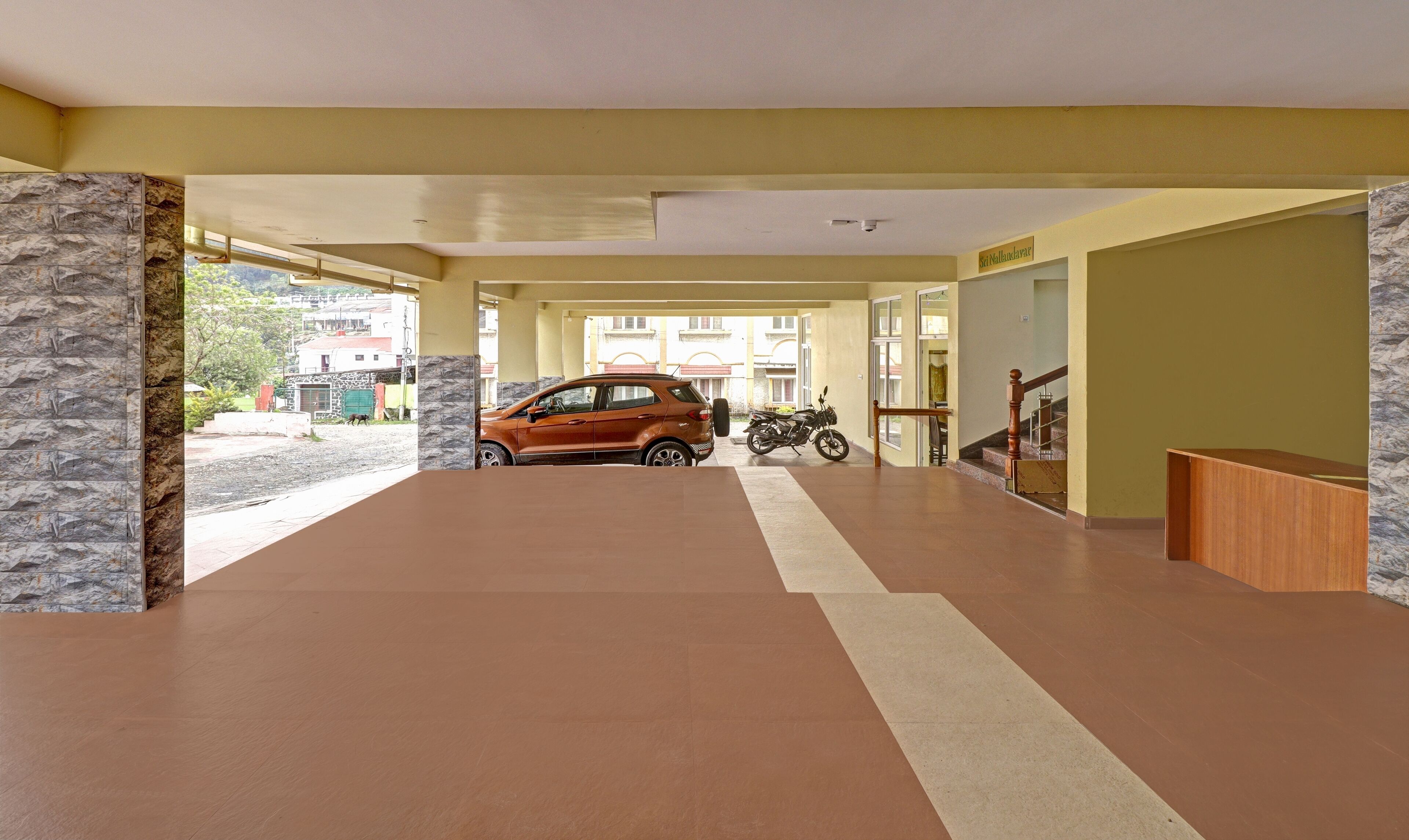 Un área de estacionamiento techada con un coche y una motocicleta, una escalera y vistas de edificios.