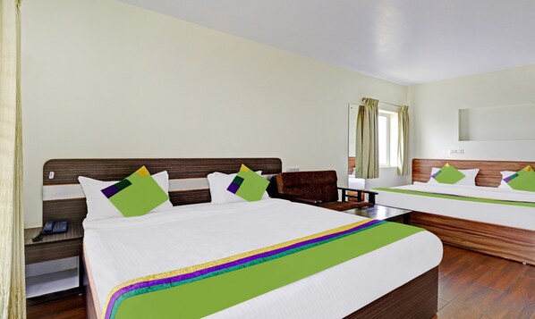 A hotel room with two beds, a wooden headboard, a bedside table with a phone, and a window with curtains. - Treebo Aall Season (Kodaikanal)