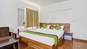 Una habitación de hotel ordenada con una cama de madera, una mesita de noche, una silla y un espejo.