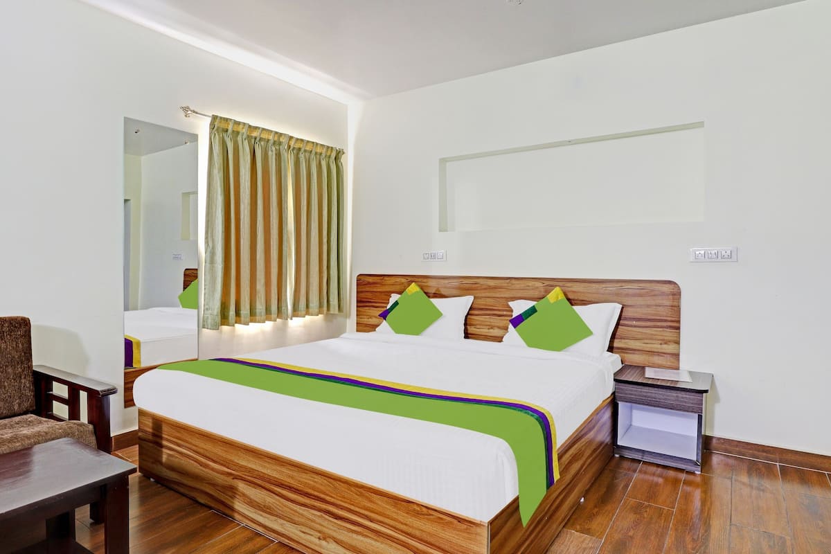 Een keurig opgemaakt hotelkamer met een houten bed, een nachtkastje, een stoel en een spiegel.