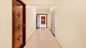 Un pasillo con una puerta de madera a la izquierda, una puerta con un diseño geométrico en el centro y una puerta con un motivo de diamantes a la derecha.