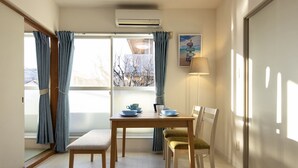 A dining area with a table, chairs, and a window with curtains.