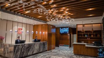 A hotel reception area with marble counters, wooden paneling, and a ceiling with hanging crystal-like decorations.