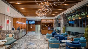A hotel lobby with a reception desk, seating area, and a large chandelier.