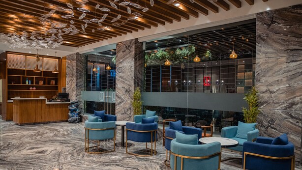 A modern lobby with marble flooring, blue upholstered chairs, and a reception desk.