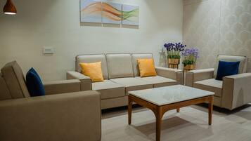 A modern living room with a beige sofa set, a wooden coffee table, and a wall-mounted abstract art piece.
