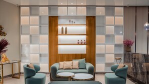 A modern lobby with a sofa set, two round tables, and a bench.