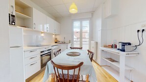Eine moderne Küche mit weißen Schränken, einem Esstisch mit Stühlen und einem Fenster für natürliches Licht.