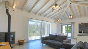 A spacious living room with a modern fireplace, a large sofa, and a dining area. - Villa Loki in Kremithas (Corfu)