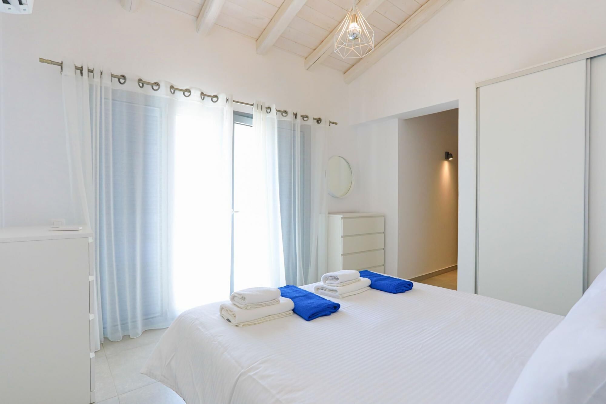 Une chambre d’hôtel avec un lit, une commode et une salle de bain visible à travers une porte ouverte.