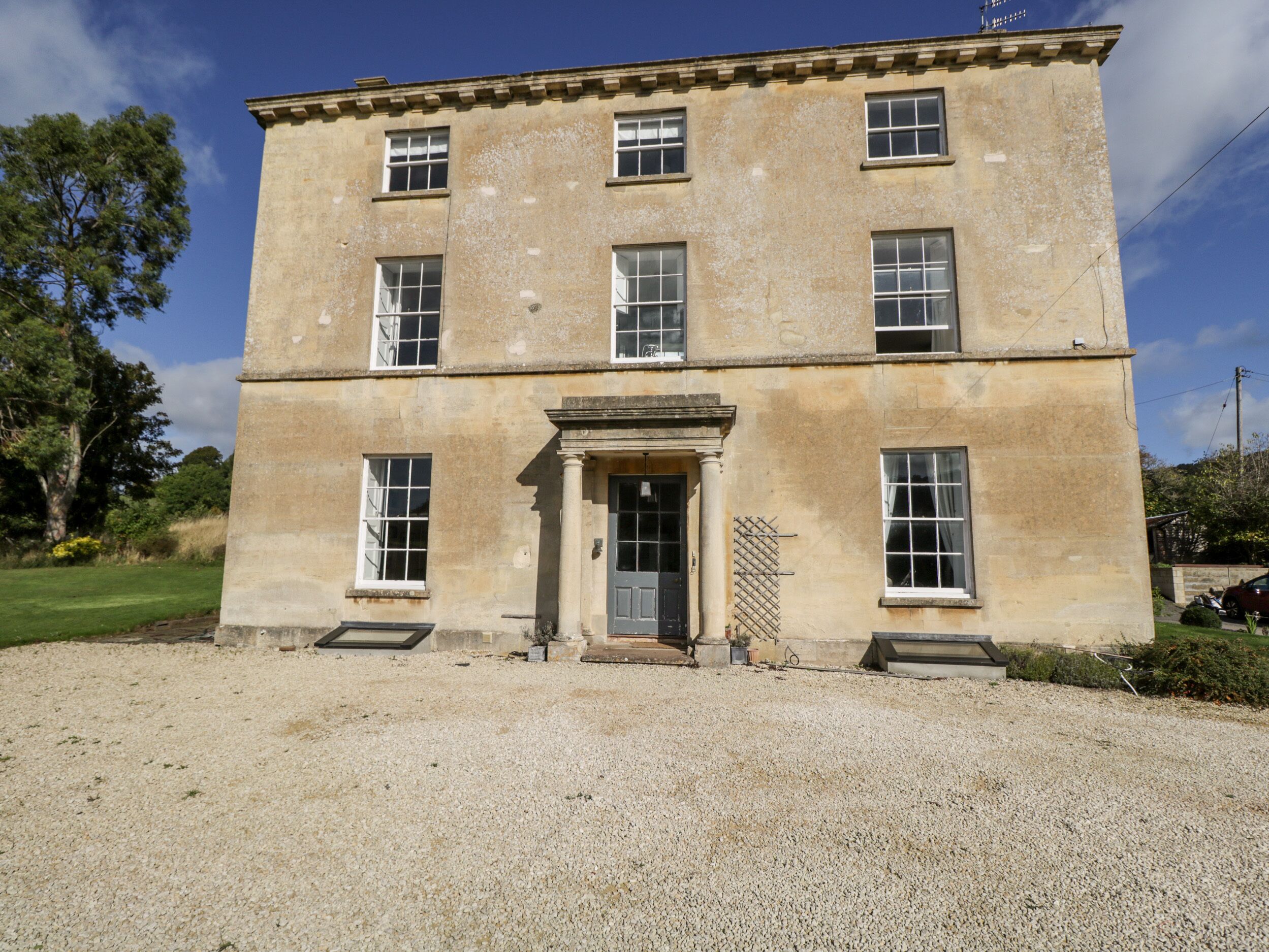 Un bâtiment à deux étages doté d’une façade symétrique, de grandes fenêtres et d’une entrée centrale avec une porte et un petit porche.