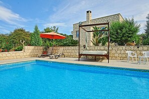 A swimming pool with lounge chairs and a wooden pergola. - Villa Georgios Rafaela (Goudi)