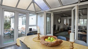 Un invernadero con una mesa dispuesta para cenar, con un frutero y velas.