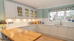 Una cocina moderna con armarios blancos, una isla de madera y un ventanal con vistas.