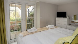 Una habitación de hotel con una cama, televisor, cómoda y puerta corrediza de vidrio que da a un balcón.