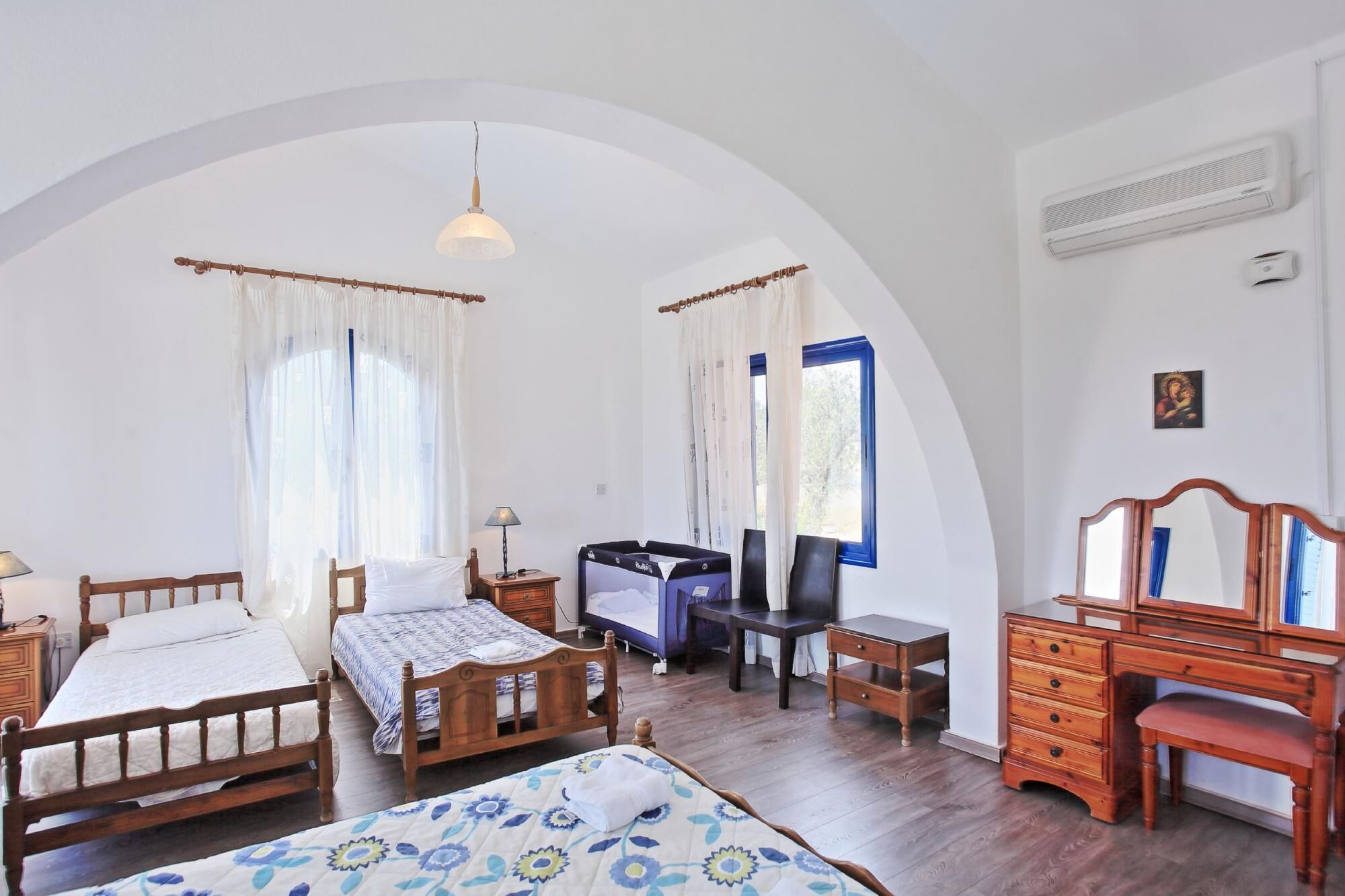 A bedroom with two wooden beds, a desk, a chair, a TV, and a mirror.