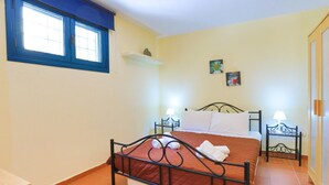 A bedroom with a bed, two bedside tables, a window, and a painting on the wall. - Tinas Apartment in Mparmpati (Corfu)