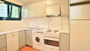 A compact kitchen with a dishwasher, washing machine, stove, and oven. - Tinas Apartment in Mparmpati (Corfu)