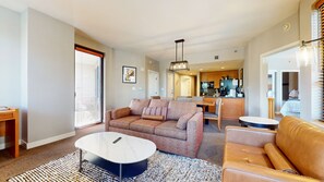 A living room with a sofa, coffee table, and a dining area with chairs.