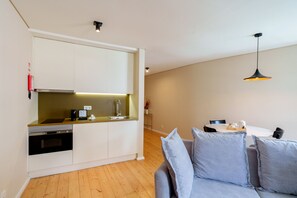 A modern kitchen with built-in appliances, a dining area with a table and chairs, and a gray sofa. - Superior One Bedroom for 3 Apart in Center (Oporto)